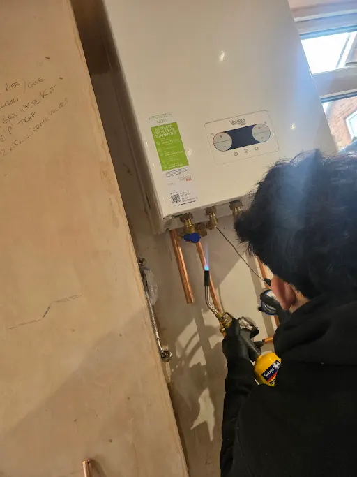 Engineer soldering copper pipes on Vokera boiler